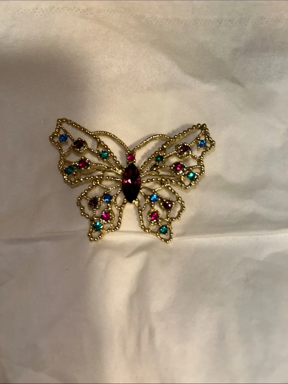 Dodds filigree butterfly brooch featuring a large amethyst-colored center stone